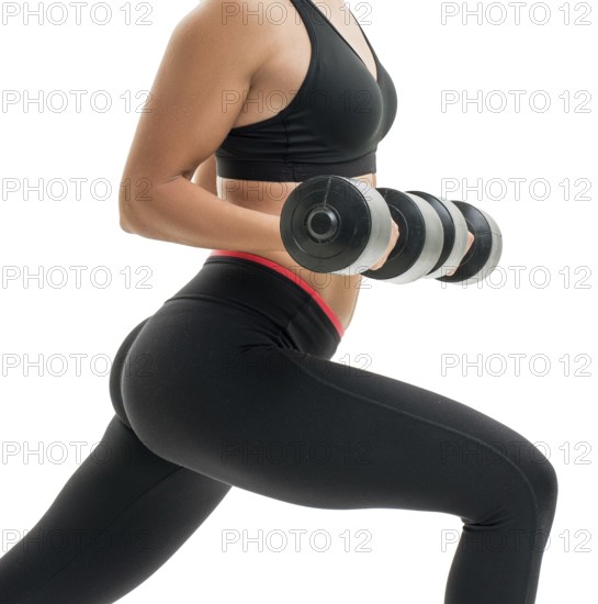 Pretty fitness trainer in black top and leggings exercising with dumbells in studio isolated photo