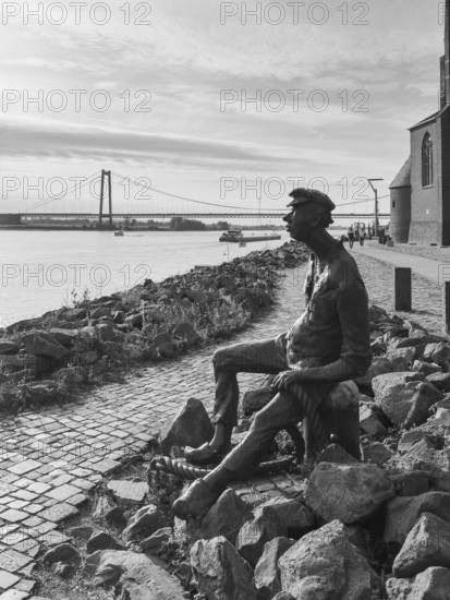 Black and white photo bronze sculpture Poortekerl looking at ships on Rhine Rhine Rhine river shipping, bronze statue by artist Heide Friede-Kinalzik, Emmerich, Lower Rhine, North Rhine-Westphalia, Germany