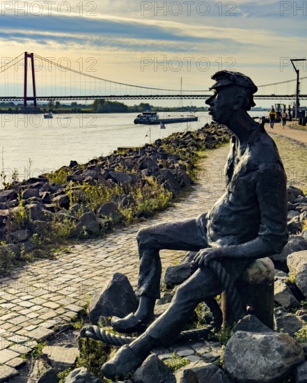 Photo with melancholy mood of bronze sculpture Poortekerl looking at Rhine waiting for ship to unload, Rhine navigation inland shipping, reminiscence of old times, bronze statue by artist Heide Friede-Kinalzik, Emmerich, Lower Rhine, North Rhine-Westphalia, Germany