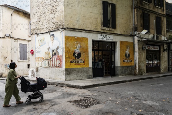 Woman with stroller, wall painting, advertisement, 1950s, corner house with old advertisement, Arles, France