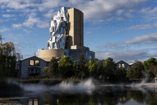 Front lake with artificial fog, Luma, 56 m high irregular tower designed by Frank Gehry, tower in the style of deconstructivism, Arles, France