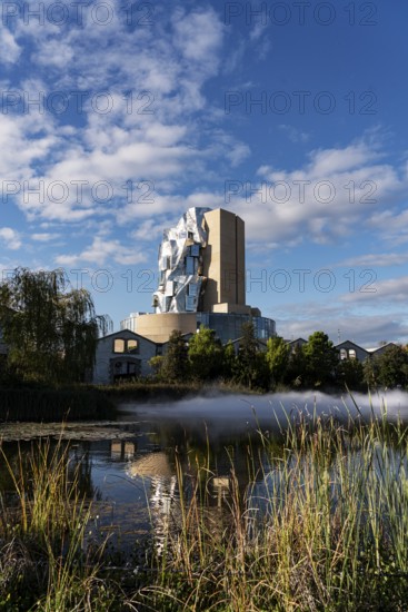 Front lake with artificial fog, Luma, 56 m high irregular tower designed by Frank Gehry, tower in the style of deconstructivism, Arles, France