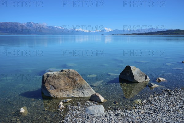 Large stones on clear lakeside with mountains in the background, Lake Pukaki Viewpoint, Pukaki, Canterbury, South Island, New Zealand