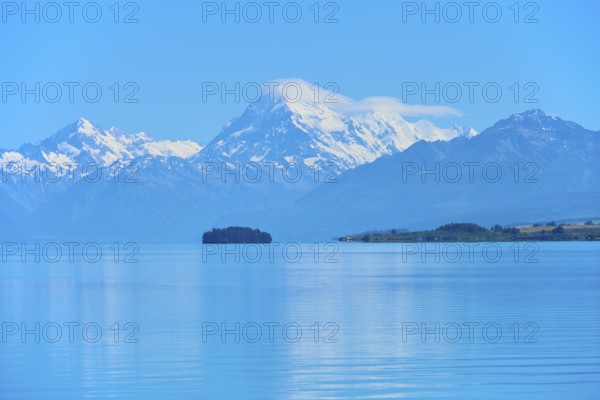 Large snow-capped mountain Mount Cook over a calm blue lake with a small island, Lake Pukaki Viewpoint, Pukaki, Canterbury, South Island, New Zealand