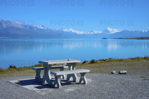 A lakeside picnic table with views of snow-capped mountains and calm water, Lake Pukaki Viewpoint, Pukaki, Canterbury, South Island, New Zealand