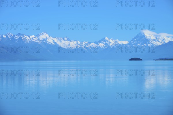 Calm lake with snow-capped mountains Mount Cook and a small island in the background, Lake Pukaki Viewpoint, Pukaki, Canterbury, South Island, New Zealand