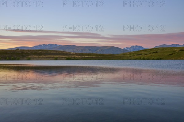 Clear lake with mountains in the background under a pink-blue morning sky, Lake McGregor, Tekapo, Canterbury, South Island, New Zealand