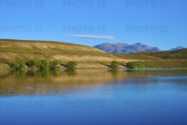 Blue sky over a calm lake with mountains in the background, Lake McGregor, Tekapo, Canterbury, South Island, New Zealand