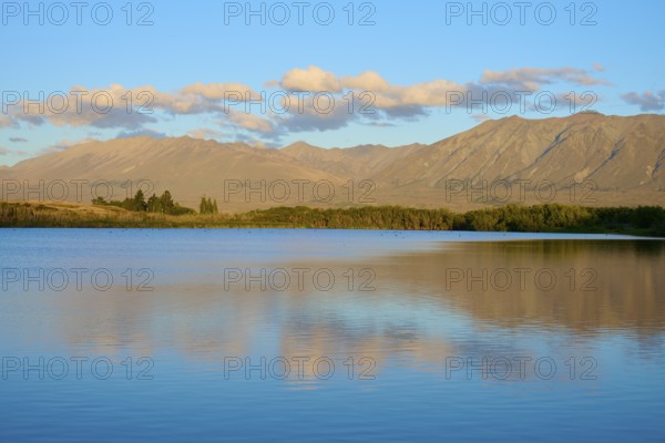 Evening over a calm lake with mountain range and beautiful cloud formation, Lake McGregor, Tekapo, Canterbury, South Island, New Zealand