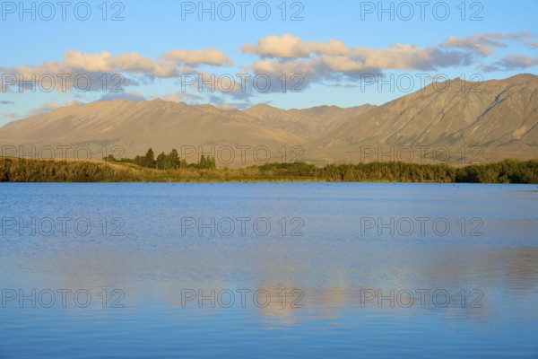 Extensive seascape in evening light with rolling mountains and cloudy skies, Lake McGregor, Tekapo, Canterbury, South Island, New Zealand