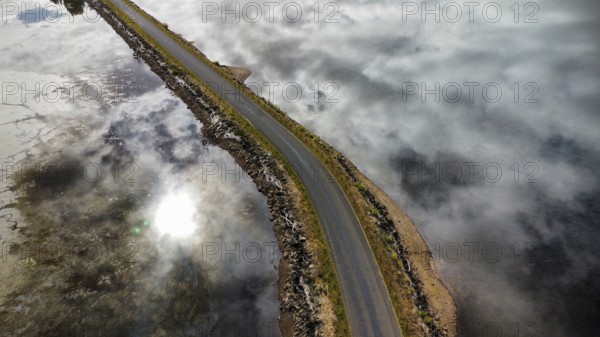 A long bridge over a shallow and calm lake on a cloudy day, photographed with a drone