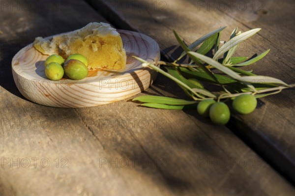 Freshly picked green olives, an olive branch, and rustic bread on a wooden surface, suggesting mediterranean cuisine and healthy eating