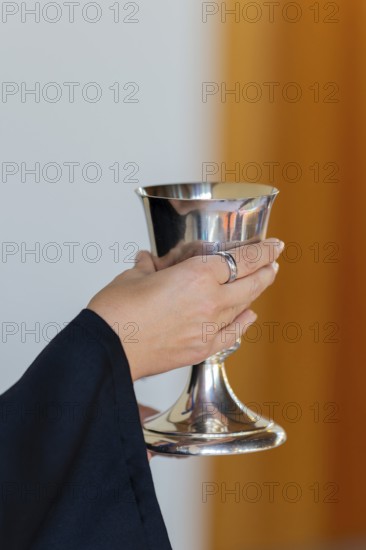 A pastor holds the chalice in both hands to present the drink during Holy Communion in Markt Swabia, Bavaria, Germany