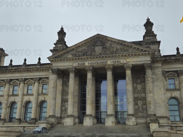 The Reichstag building, magnificent parliament façade with inscription and tall pillars, frontal in grey weather, government district in 11011 Berlin, Germany
