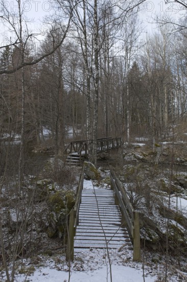 Old wood walking bridges over river Mustionjoki in cloudy winter weather, Junkarsborg, Finland