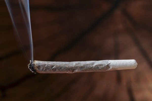 Burning joint producing smoke, highlighting drug use, cannabis culture, addiction, and illegal substances