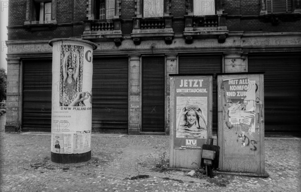 Germany, Berlin, 3.8.1992, advertising column and telephone booths, in front of closed shutters in Pappelallee, corner ~, now dive into hiding, today a café