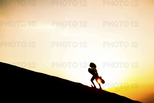 Silhouette of a sandboarder walking on the dunes of Caramucho, in Atacama Desert. Iquique, Tarapaca Region, Chile. 21.11.15