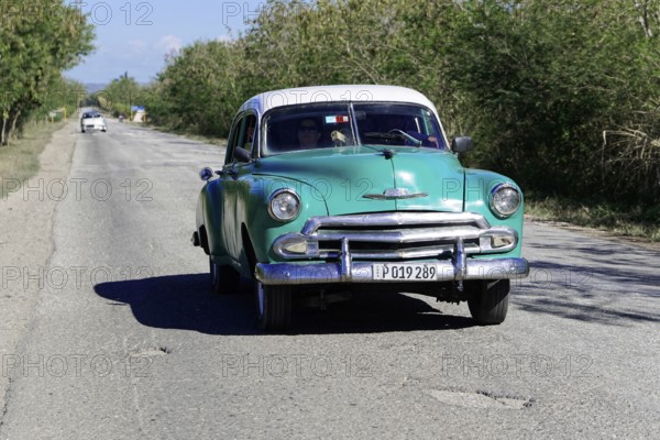 American classic car from the 1950s, near Holguin, Cuba, Vintage green car driving along a rural road along trees, Greater Antilles, Caribbean, Central America, America, Central America
