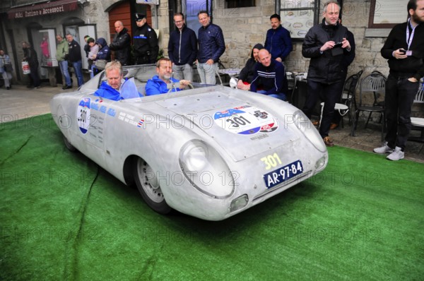 Aluminum-colored racing roadster with blue drivers at a vintage car rally on green carpet, purist appearance, Mille Miglia 2016, time control, checkpoint, SAN MARINO, classic car racing. San Marino, Italia