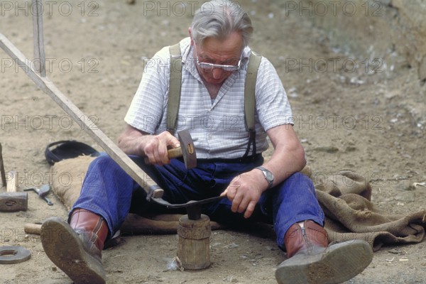 Farmer sharpening a scythe, Franconia, Bavaria, Germany