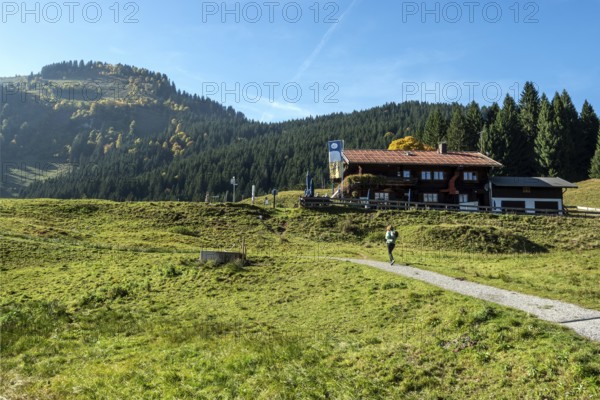 Female hiker on hiking trail in front of Berggasthof Hochleite, near Schwand, Stillachtal, Oberstdorf, Oberallgäu, Allgäu, Bavaria, Germany