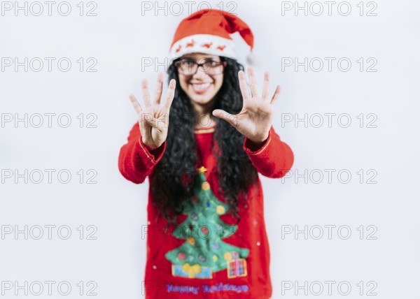 Happy girl in Christmas hat counting number NINE, isolated. Smiling girl in Christmas sweater counting number 9