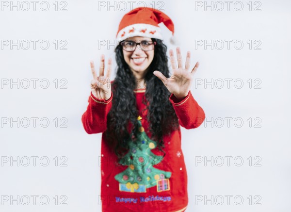Happy girl in Christmas hat counting number EIGHT, isolated. Smiling girl in Christmas sweater counting number 8