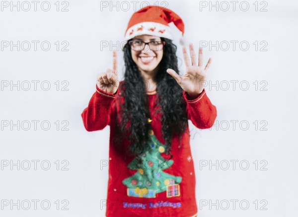 Happy girl in Christmas hat counting number SIX, isolated. Smiling girl in Christmas sweater counting number 6