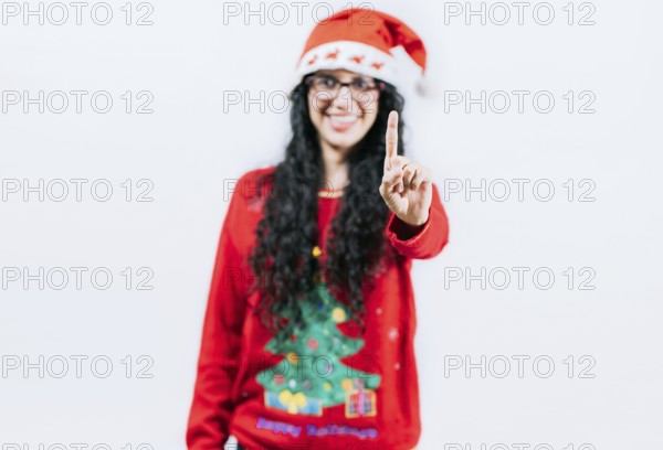 Happy girl in Christmas hat counting number ONE, isolated. Smiling girl in Christmas sweater counting number 1