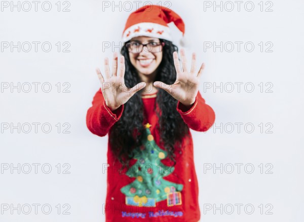 Happy girl in Christmas hat counting number TEN, isolated. Smiling girl in Christmas sweater counting number 10
