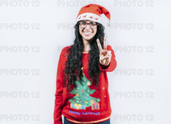 Happy girl in Christmas hat counting number two, isolated. Smiling girl in Christmas sweater counting number 2