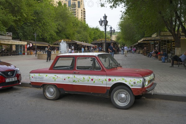 Red retro car parked in front of busy market square with green trees, SAS-968, Zaporoshez, Yerevan, Yerevan, Armenia