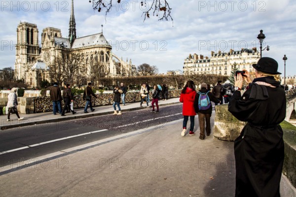 Tourists on Pont de l'Archevêché and Notre Dame Cathedral (Cathedrale Notre Dame de Paris) in the background. Paris, France. 02.01.13