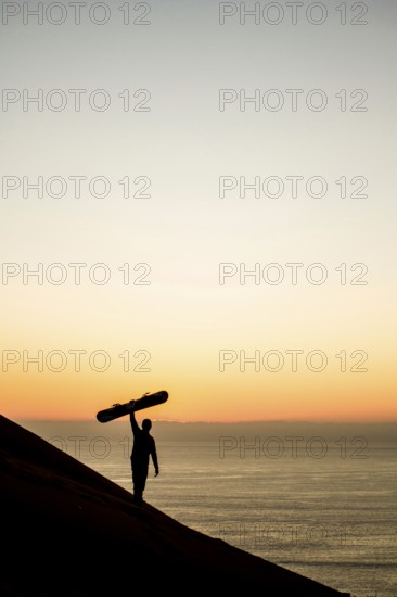 Silhouette of a sandboarder in Cerro Dragon at sunset, a sand dune located next to the city of Iquique, in Atacama Desert. Iquique, Tarapaca Region, Chile. 15.11.15