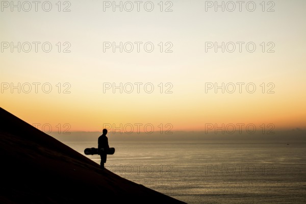 Silhouette of a sandboarder in Cerro Dragon at sunset, a sand dune located next to the city of Iquique, in Atacama Desert. Iquique, Tarapaca Region, Chile. 15.11.15