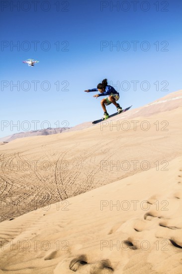 Sandboarding in Cerro Dragon, a sand dune located next to the city of Iquique, in Atacama Desert. Iquique, Tarapaca Region, Chile