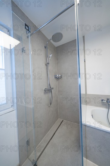 Floor-level shower with glass partition and rain shower head in calm shades of gray next to the bathtub, house renovation, energy renovation, Metzingen, Germany