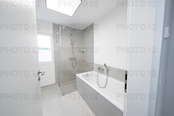 Modern bathroom with floor-level shower and tub in front of large format grey tiles and plenty of daylight, house renovation, energy renovation, Metzingen, Germany