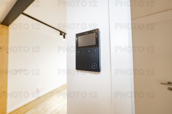 Wall intercom with display in a bright corridor next to a white door and warm parquet, house renovation, energy renovation, Metzingen, Germany