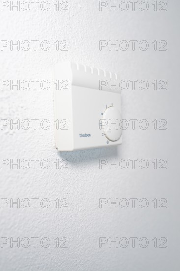Wall thermostat with rotary knob on textured white wall in a quiet, bright atmosphere, house renovation, energy renovation, Metzingen, Germany