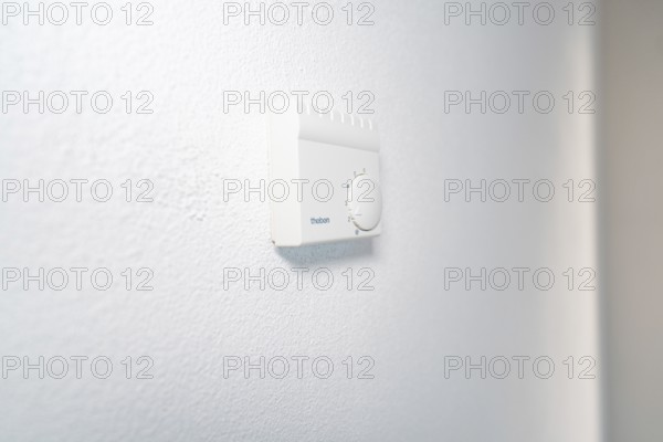 Close-up of a white room thermostat on a plastered wall in a bright, modern environment, house renovation, energy renovation, Metzingen, Germany