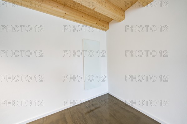 Bright corner with glass heating panel on white wall under wooden beam ceiling, reduced appearance, house renovation, energy renovation, Metzingen, Germany