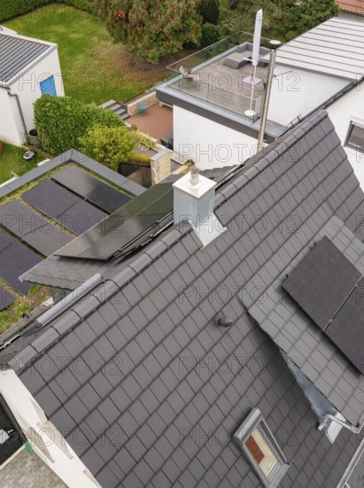Angled aerial view of a house with PV systems on roof and carport, skylight and chimney in a quiet neighborhood, house renovation, energy renovation, Metzingen, Germany