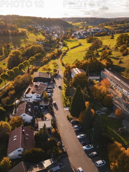 A village in autumn atmosphere with trees along the road and fields at sunset, Deufringen, Aidlingen, Böblingen district, Germany