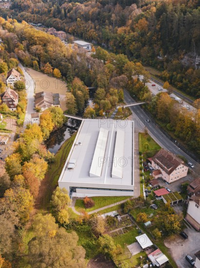 Sports hall nestled in autumn colors and surrounded by river and village road, Walter Lindner Sporthalle Calw, Black Forest, Germany