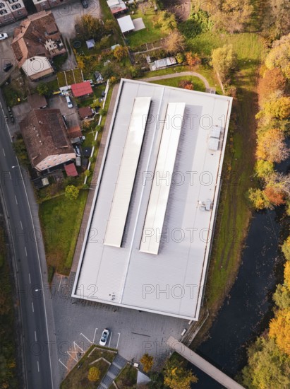 Aerial view of a sports hall with a flat roof surrounded by colorful autumn vegetation, Walter Lindner Sporthalle Calw, Black Forest, Germany