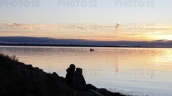 A couple sitting on the beach during sunset, Fehmarn island, 18.10.2025, Fehmarn, Schleswig-Holstein, Germany