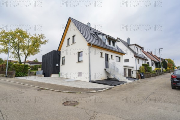 Modernized residential building on a quiet street corner with bright façade under cloudy sky, house renovation, climate renovation, Metzingen, Germany