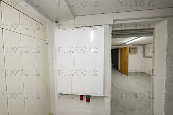 Simple basement corridor with white electrical distributor on plastered wall, objectively illuminated, access to other adjoining rooms, house renovation, air conditioning renovation, Metzingen, Germany